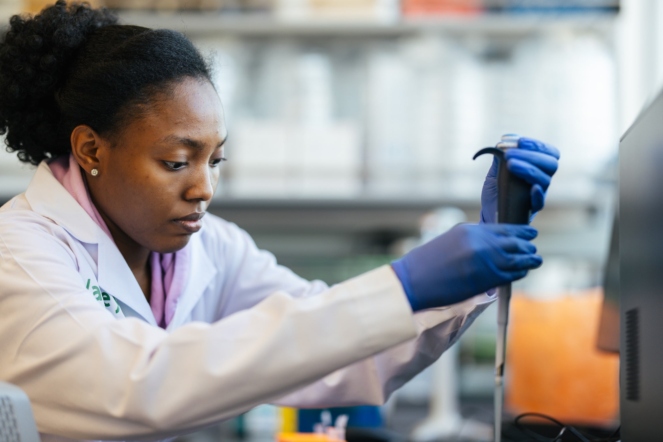 student using a pipette in a lab wearing a lab coat