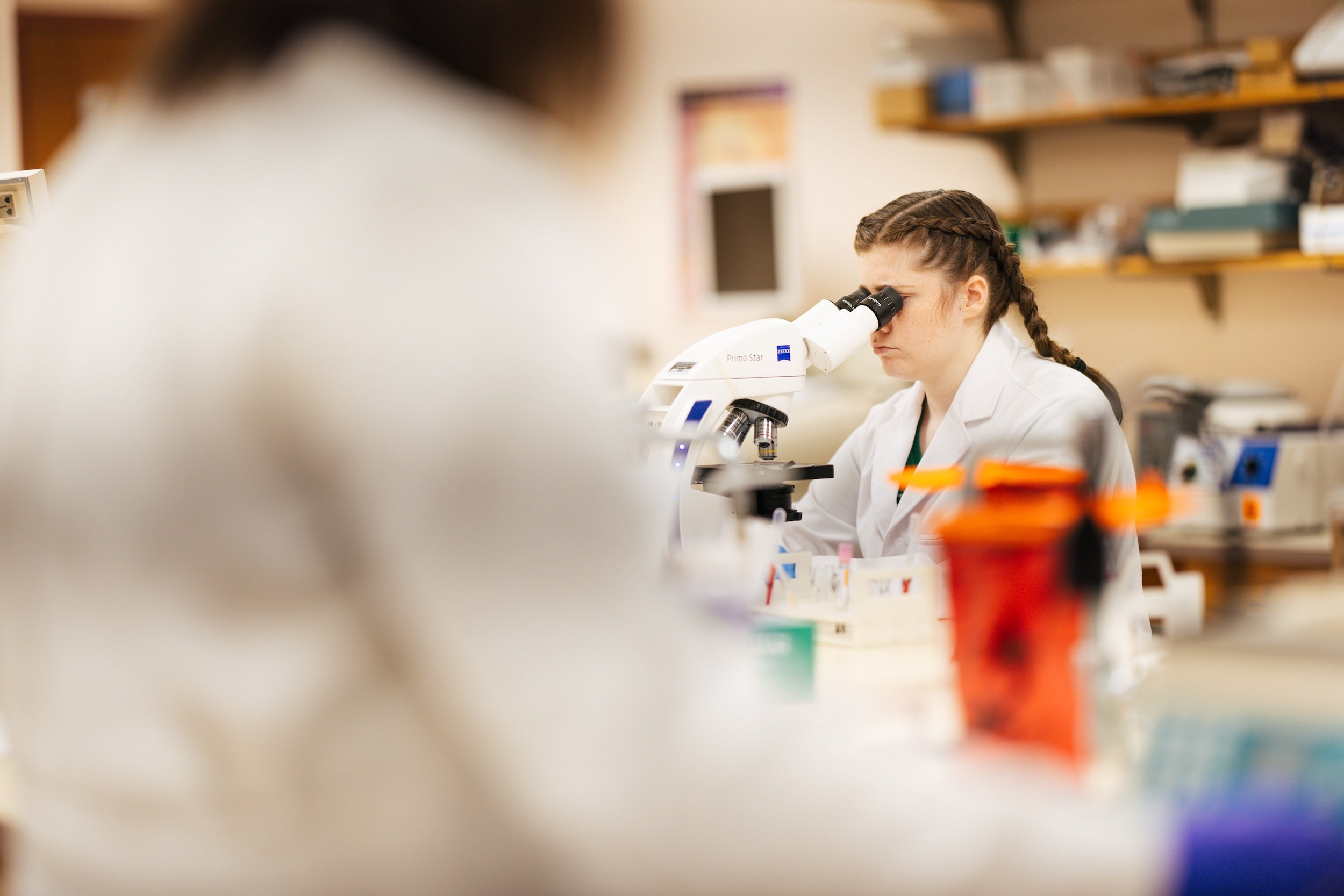 female student looking through a microscope in a laboratory