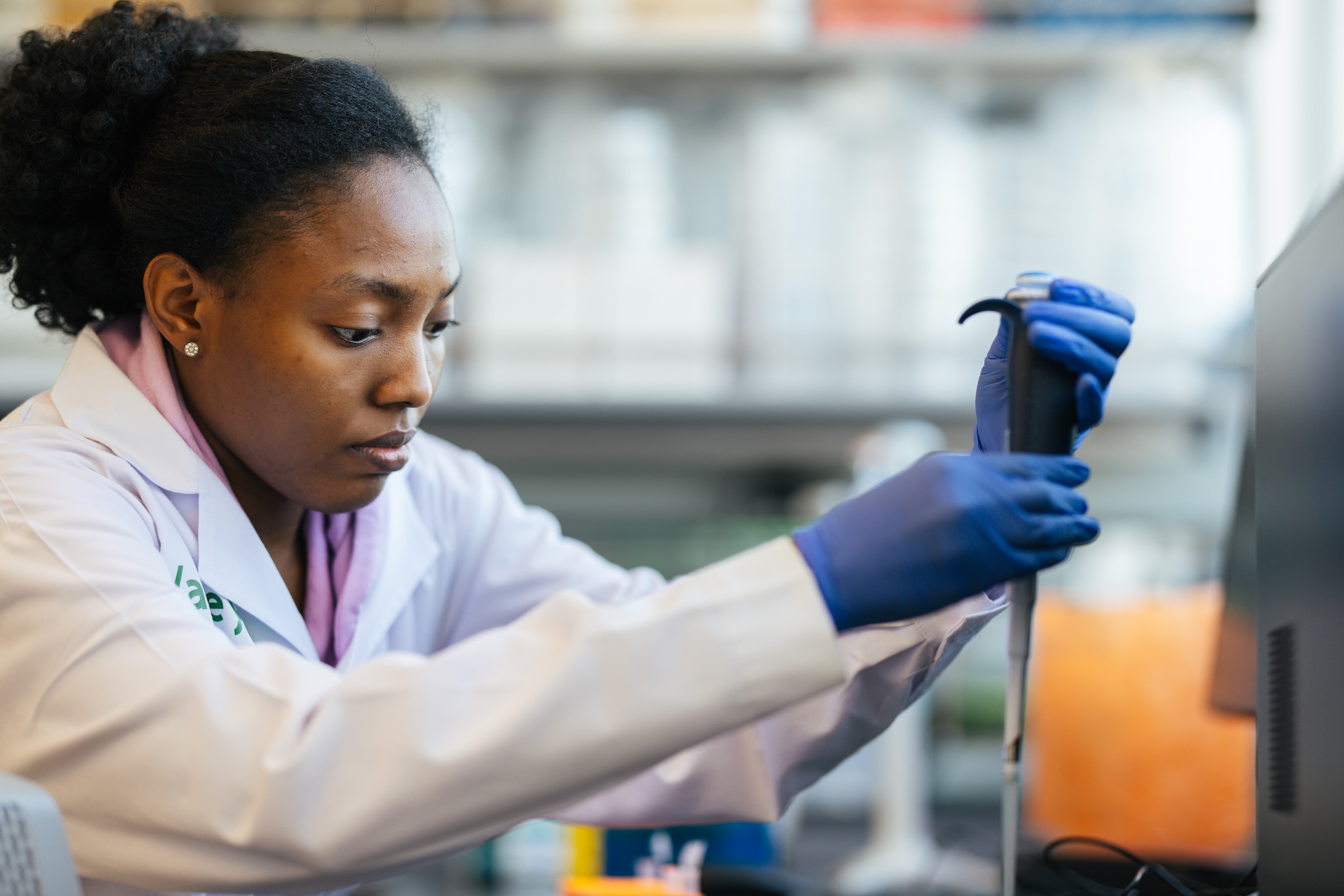 student using a pipette in a lab wearing a lab coat