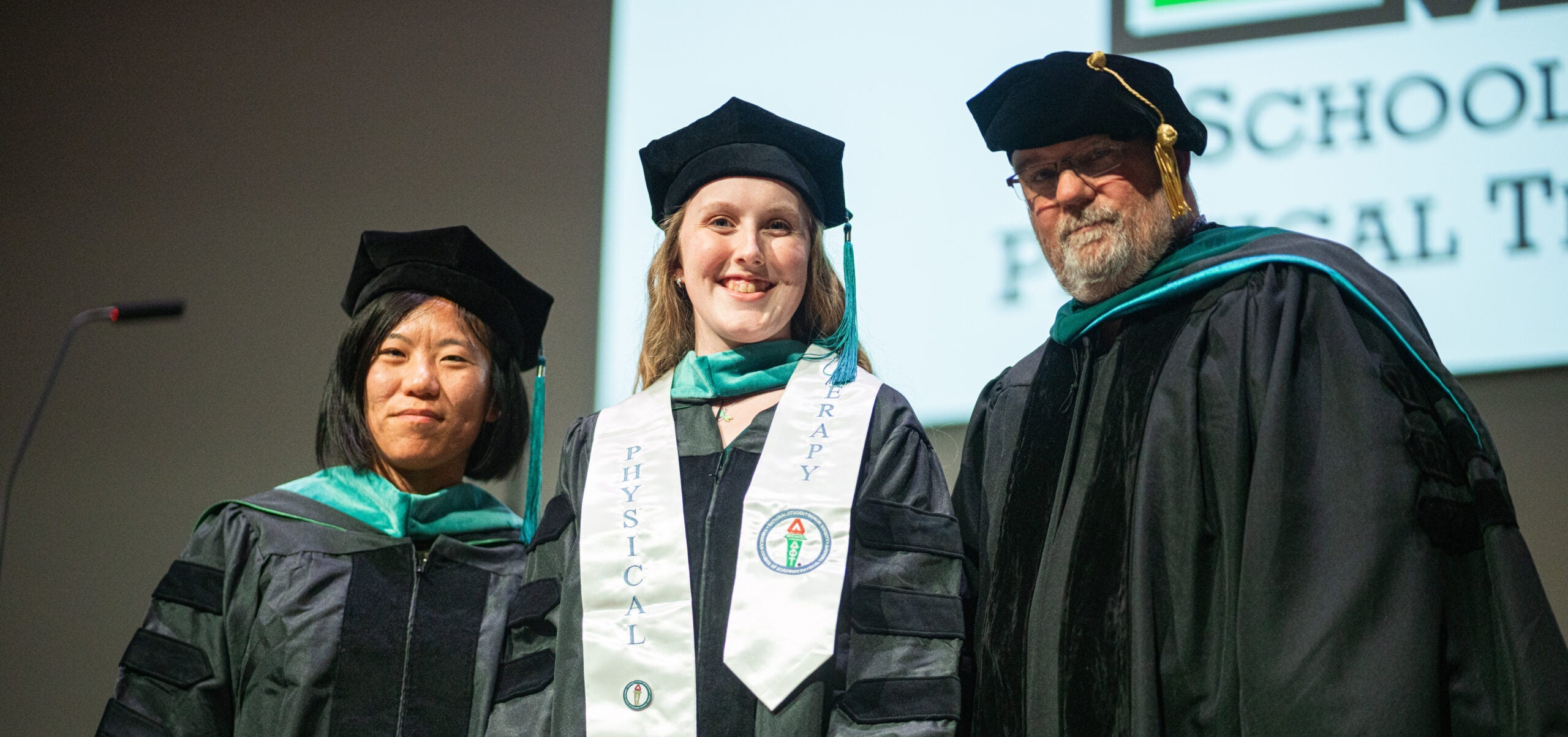 hooding ceremony photo of student with two professors