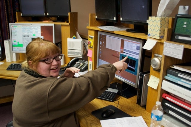 Photo of Rae Stanley pointing to a readout on a computer monitor