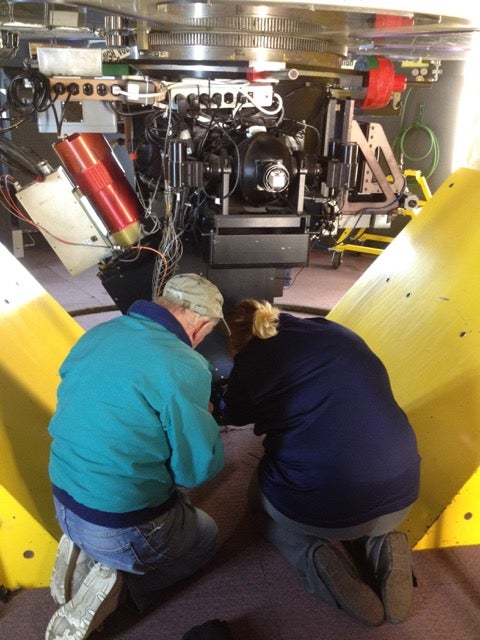 Two people working on mechanical systems at the observatory