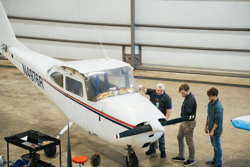 students working on an airplane in a hangar
