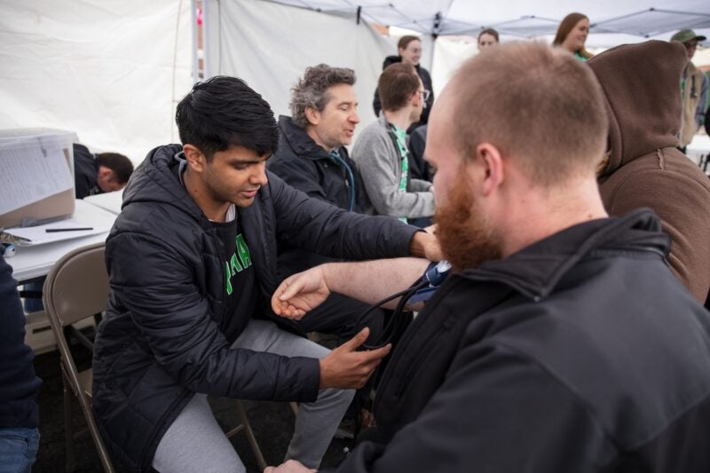 medical student taking blood pressure of a patient at Marshall Medical Outreach