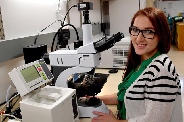Female College of Science student preparing to examine a specimen under a microscope
