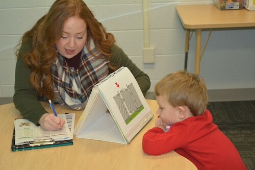 Female College of Health Professions assisting with an evaluation of a young child