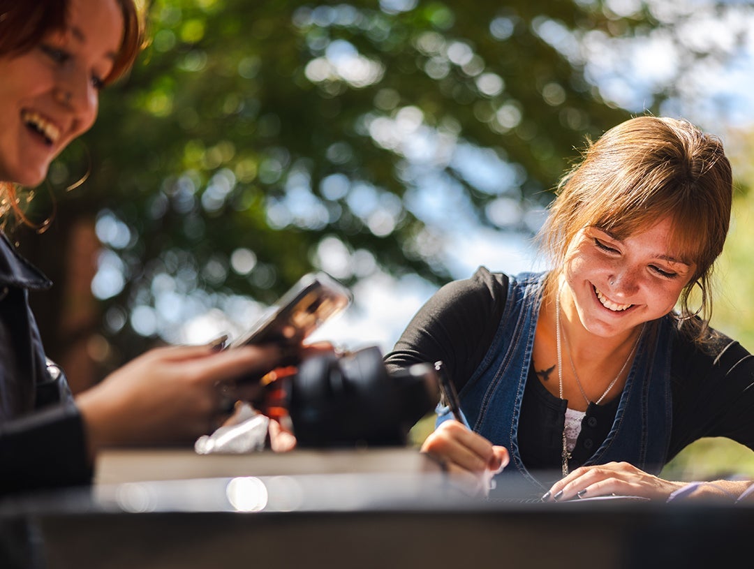 Students laugh while studing together outside