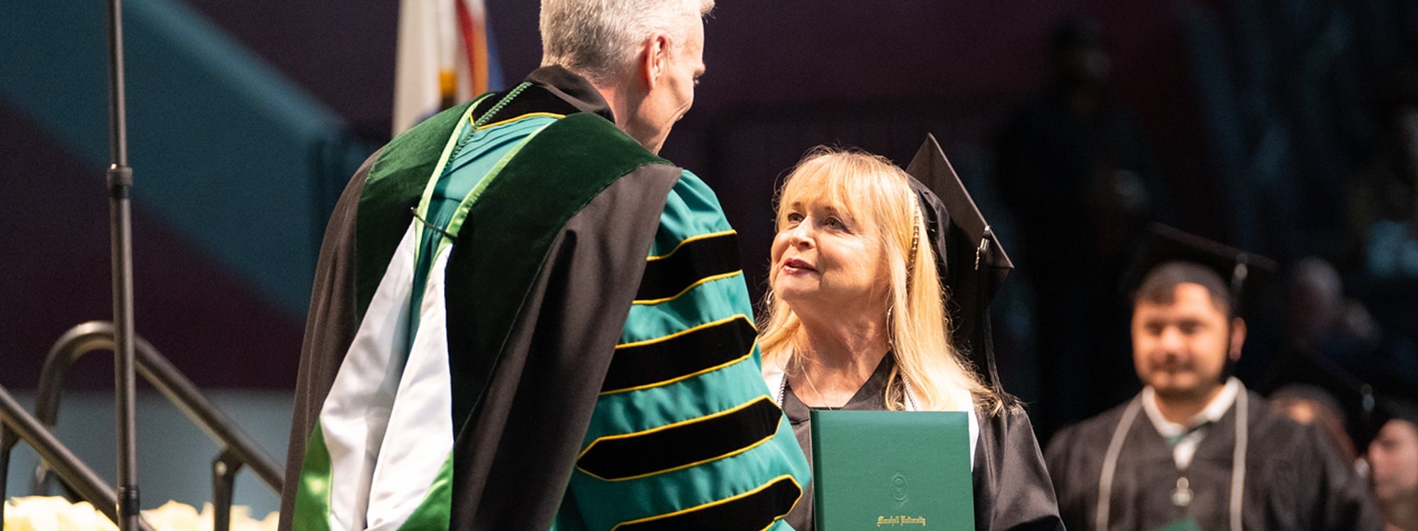 RBA graduate Kerri Barger accepts her diploma and shakes President Smith's hand at Marshall University Commencement