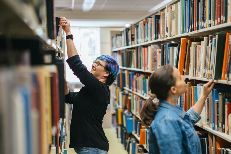 two people looking at bookshelves in the library