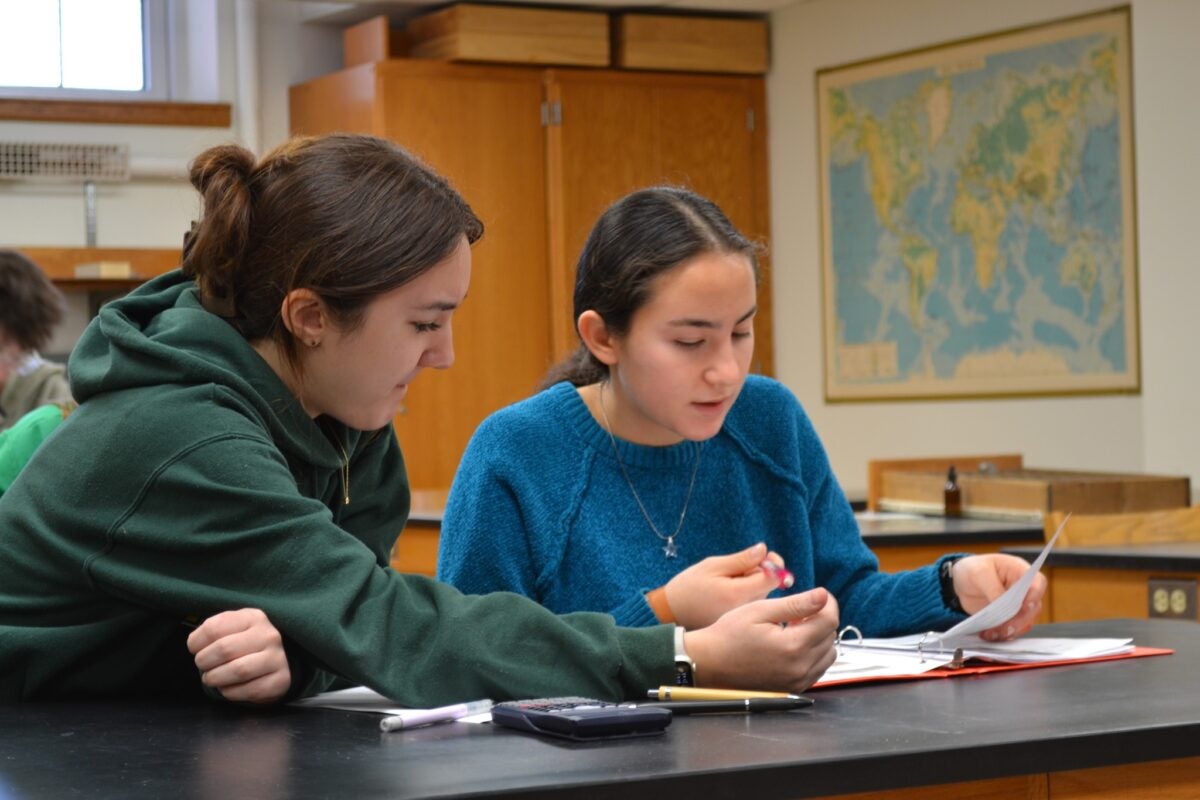two students working together on a project at a table