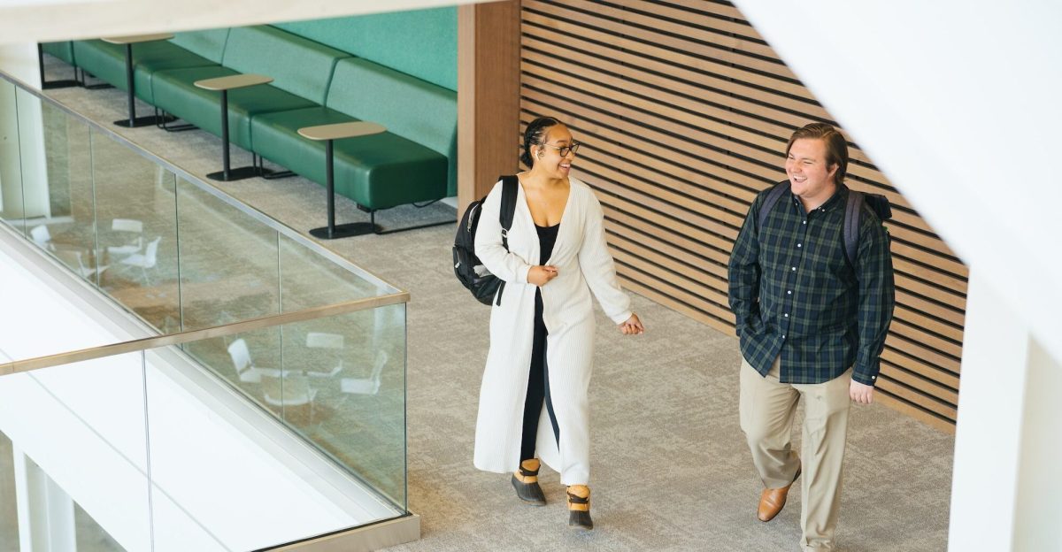two students walking and talking through the business building