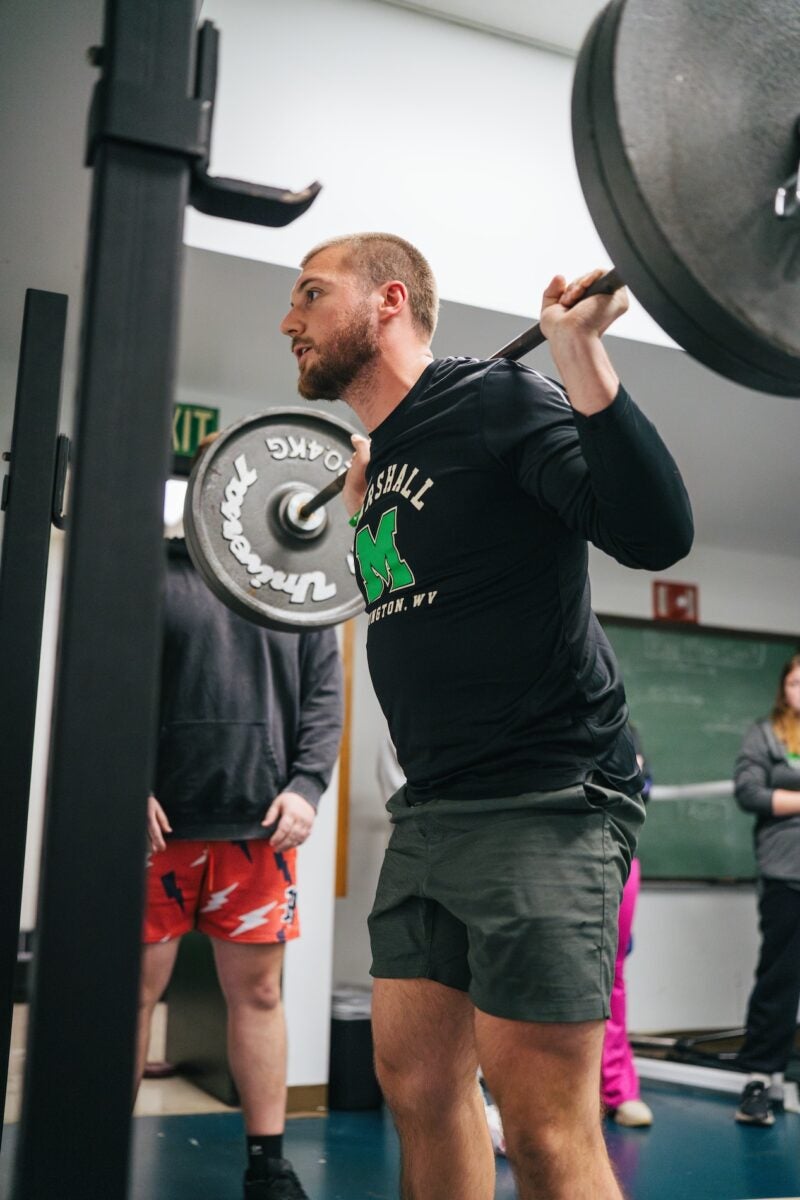 student getting ready to squat weight in the exercise science lab
