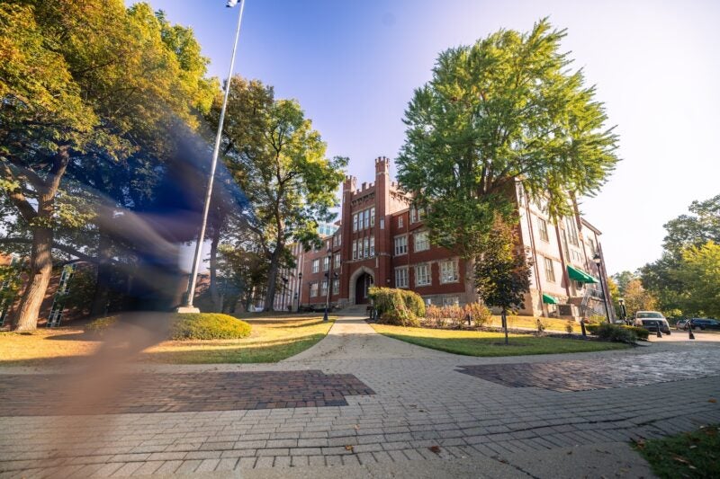 exterior of Old Main with people walking past and blurred out