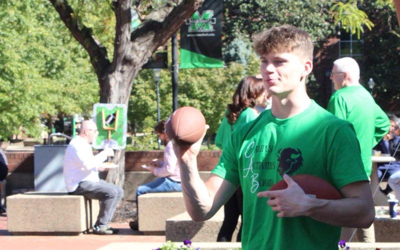 Jakob Tipton throws a football on Marshall University's Memorial Student Center Plaza