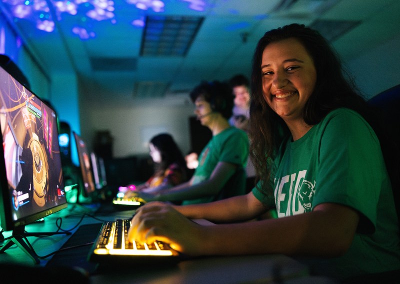 Student smiles at the camera while playing Esports in Marshall University's gaming lounge