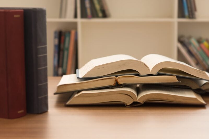 open book and books stacked on desk in library. legal education.