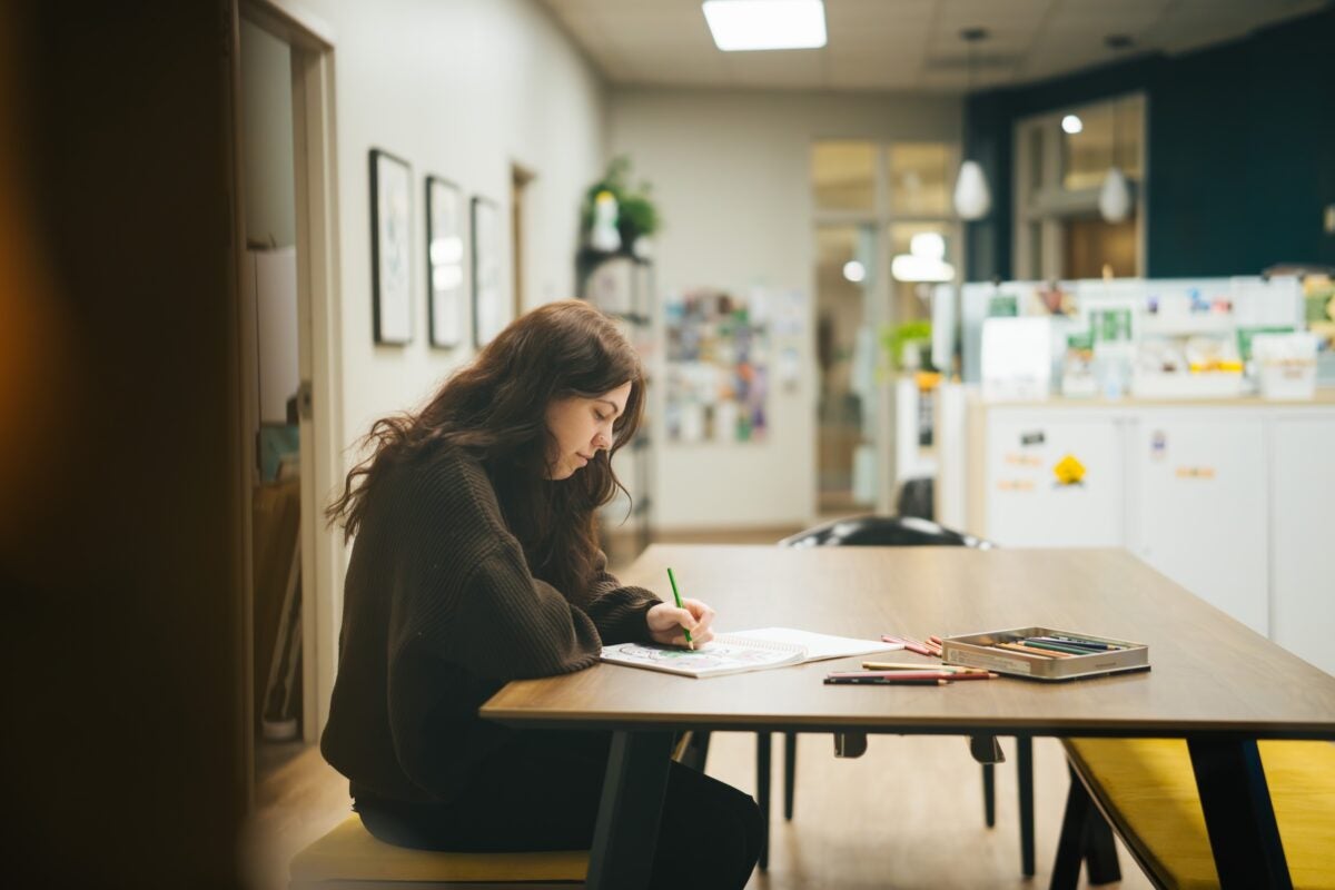 student studying at a table and taking notes independently