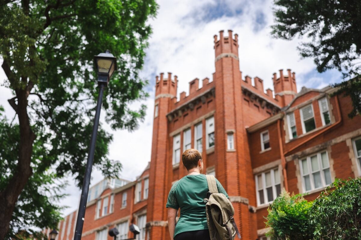 student facing Old Main with a back pack on