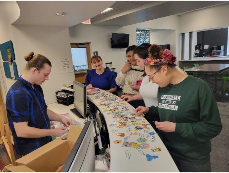 students looking at stickers at the front desk of East Hall together
