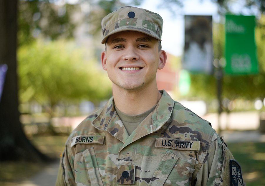 A Marshall University ROTC student stands smiling while wearing his uniform on campus