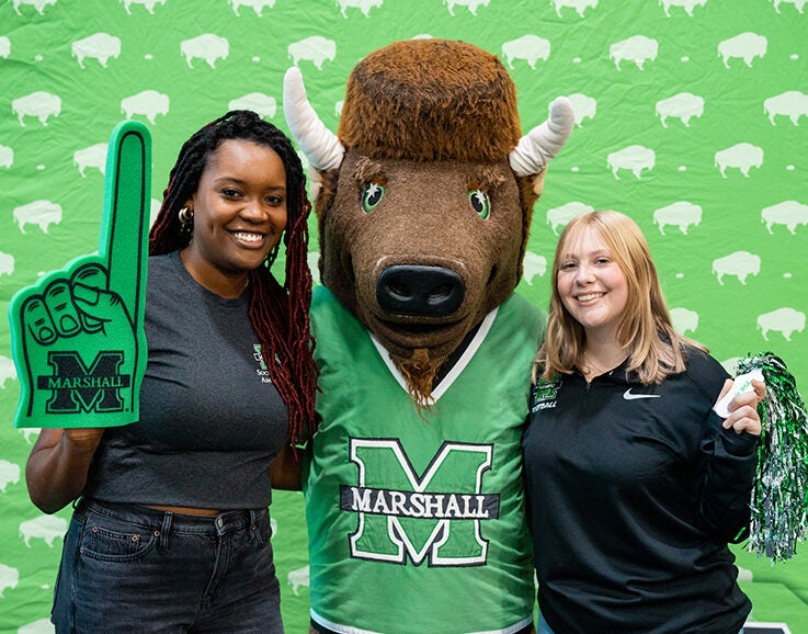 Students pose with Marco in front of a Marshall background.