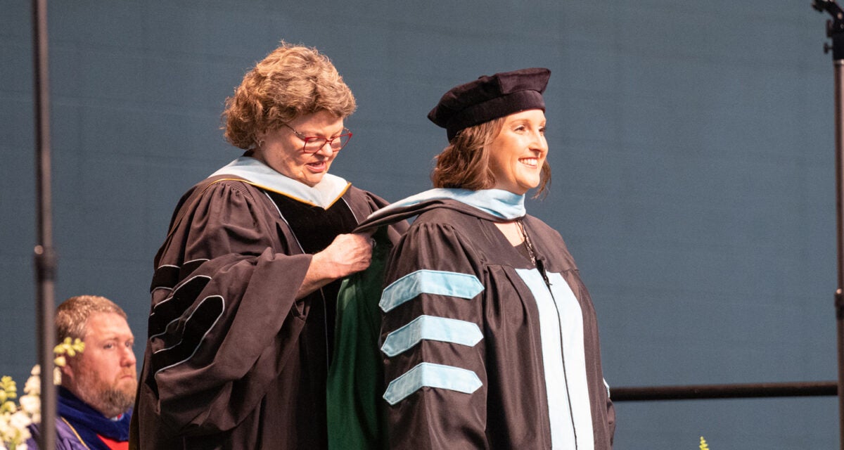 Dr. Eagle hoods an Ed.D. graduate during commencement ceremony
