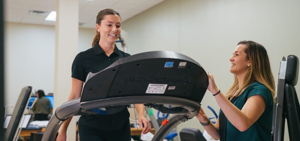 student exercising on a treadmill with a person supervising