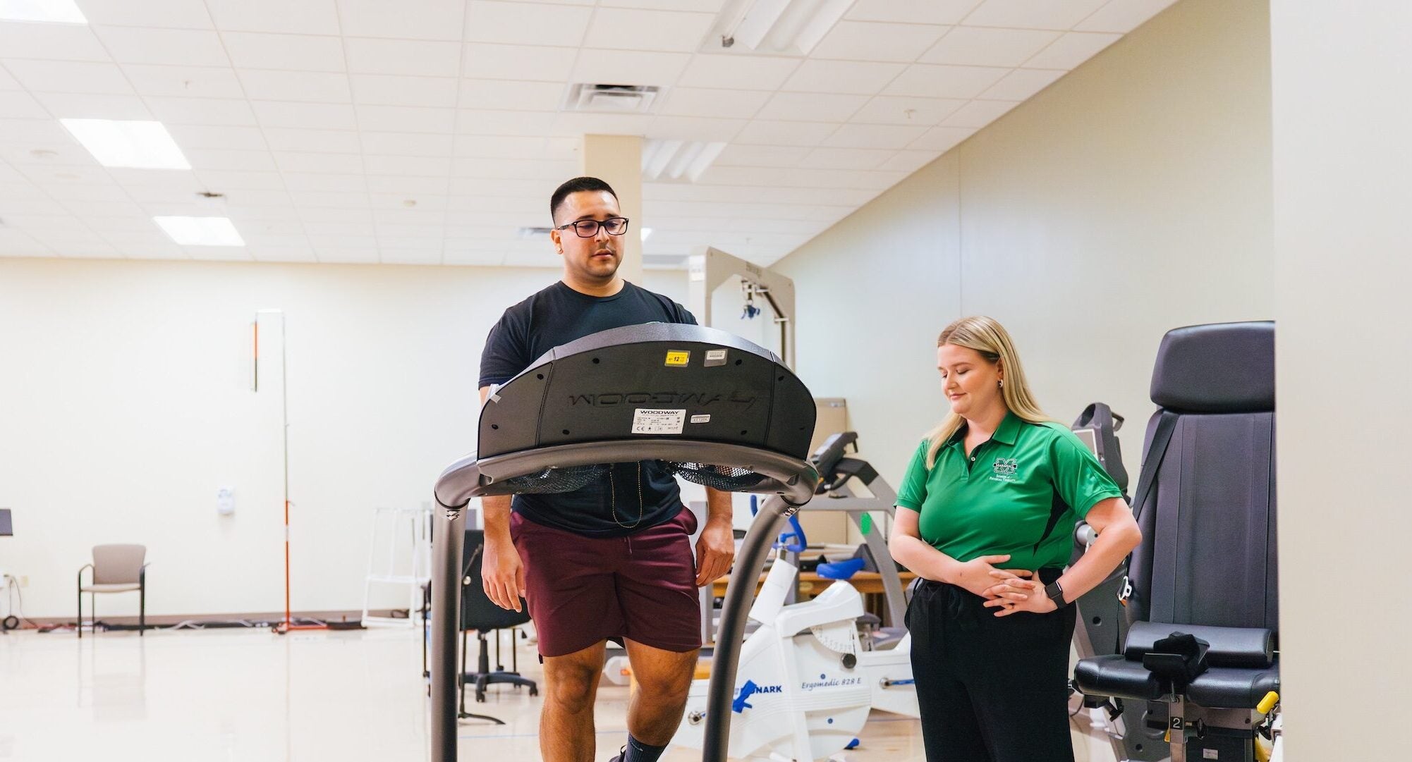 patient on a treadmill with a physical therapy student supervising