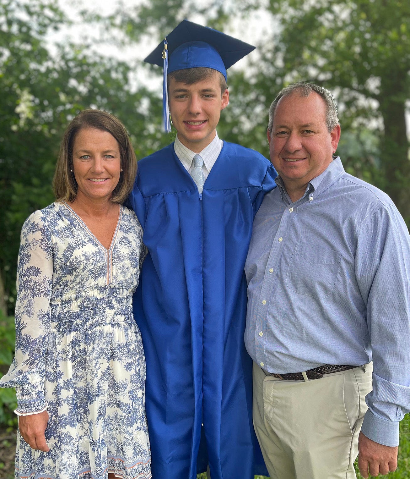 Jimmy John Jacobs smiles with his parents while wearing his high school graduation cap and gown