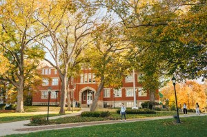 Marshall University's Old Main building framed by trees displaying golden autumn leaves.
