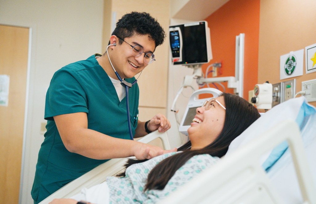 student nursing student checking for a pulse with a stethoscope on a student patient