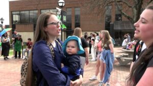 Sister Ray debates with a student while holding her baby.