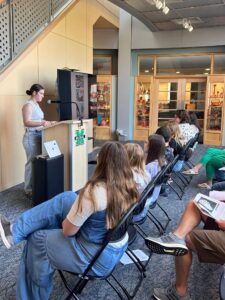 girl reading her story at a podium to an audience in a library