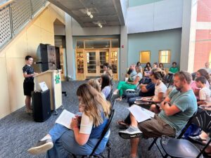 boy reading his story at a podium to an audience in a library