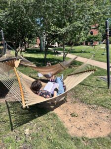 girl writing in hammock outside