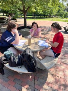 3 girs writing and collaborating at a table outside