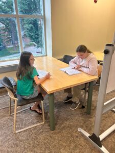 2 children writing at a table in the library
