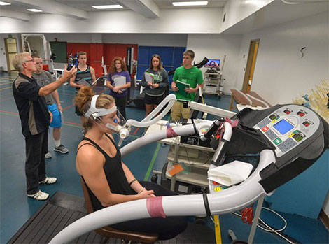 A class of students gathered around a treadmill.
