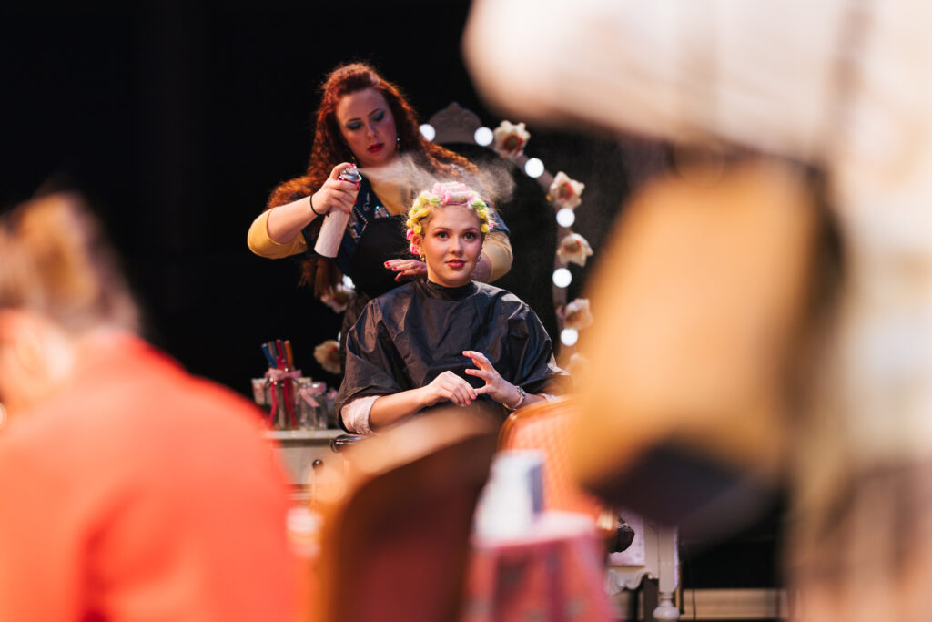 Kendra Williams styles hair on stage while playing the role of Truvy Jones.