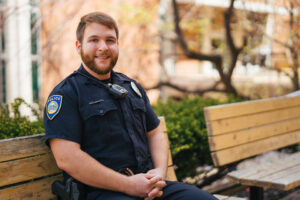 Marshall University Police Officer, Chase Poore sits on a bench on Marshall's Huntington campus