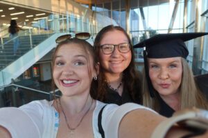 Sarah and Jackie Wazelle and their mom Nichole in a graduation cap