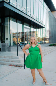 Haley Prather wears a green dress while standing in front of the Brad D. Smith Center for Business and Innovation at Marshall University