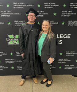 Ethan Starkey wears his cap and gown and smiles for a photo in front of a Marshall University background