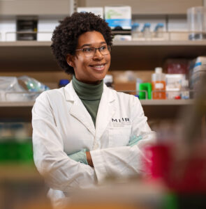 Sidney Strause stands in a lab smiling while wearing her white coat