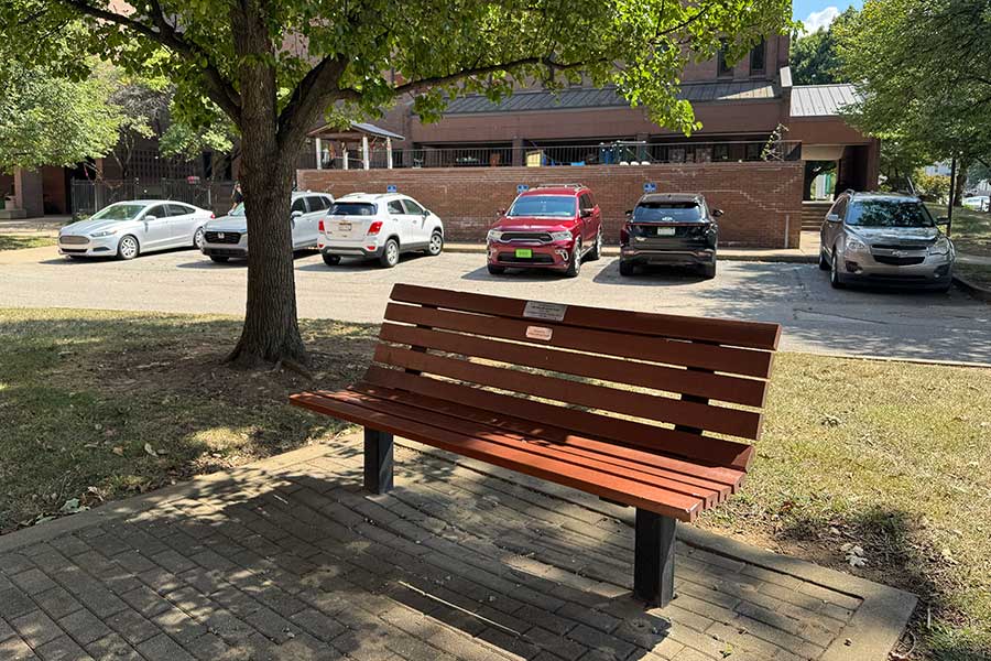 Memorial bench west of the John Deaver Drinko Library honoring Ella Marie Brumfield Zirkle, positioned beneath a mature shade tree overlooking a campus lawn and walkway.