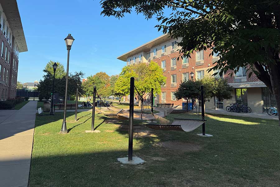 Hammocks and Adirondack chairs arranged in a grassy courtyard between Marshall University's First-Year Residence Halls, providing outdoor seating beneath shade trees and landscaped walkways.