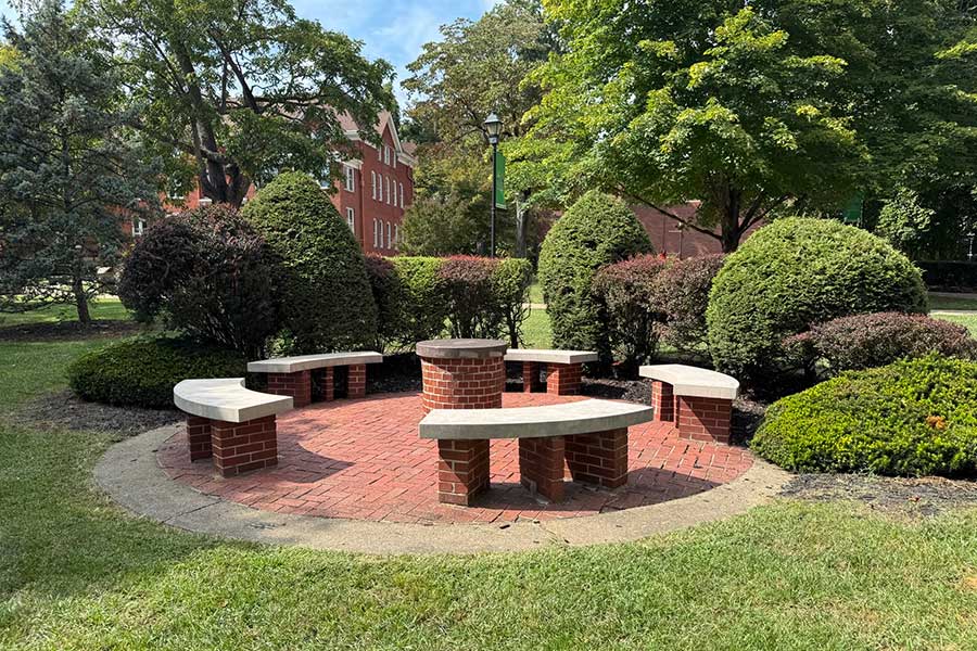 The Omicron Delta Kappa Circle near Old Main, showing brick seating, a central table, and surrounding campus landscaping used for ceremonies and outdoor classes.